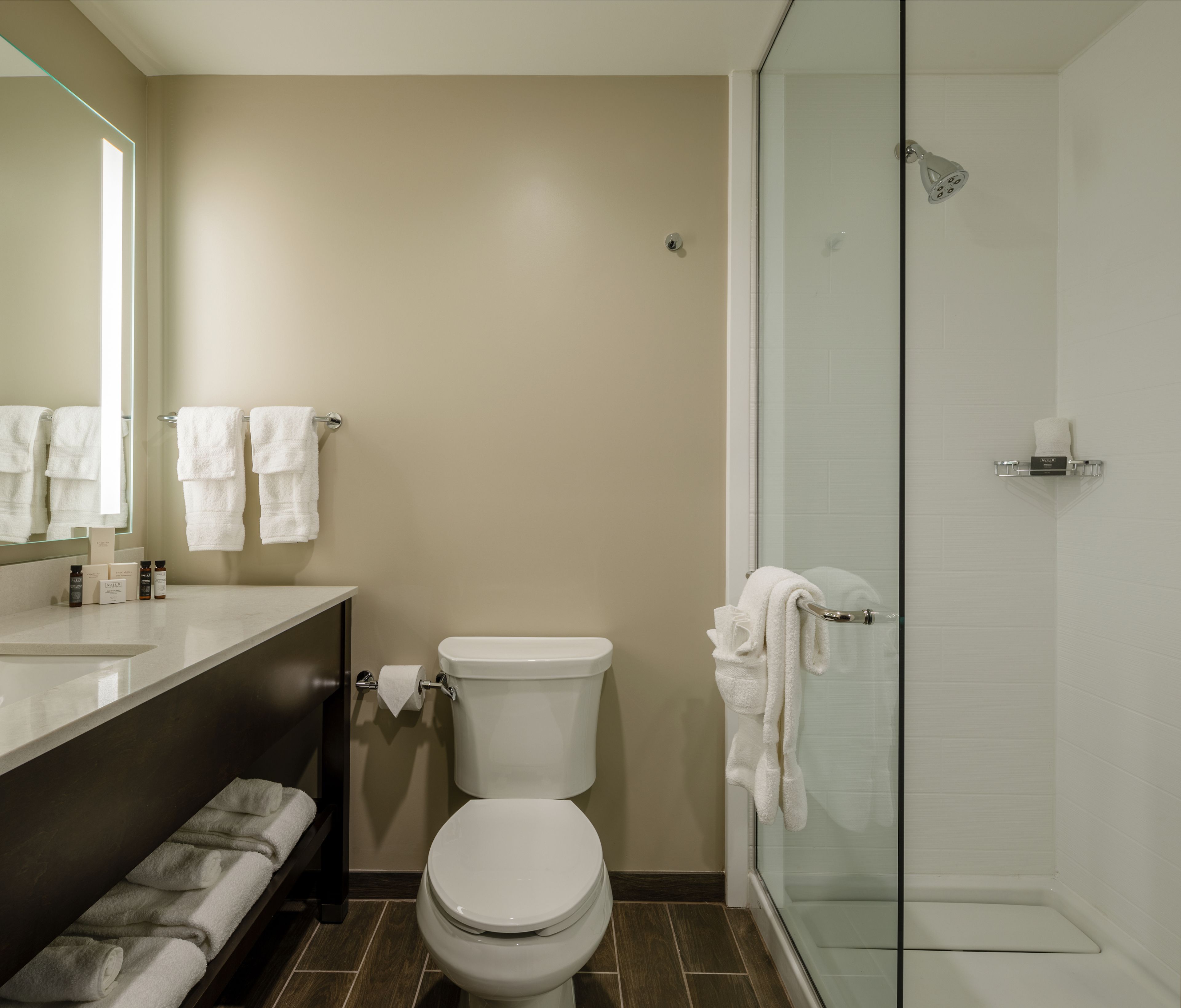 Een moderne badkamer met toilet, wastafel en douchecabine met glazen wanden.