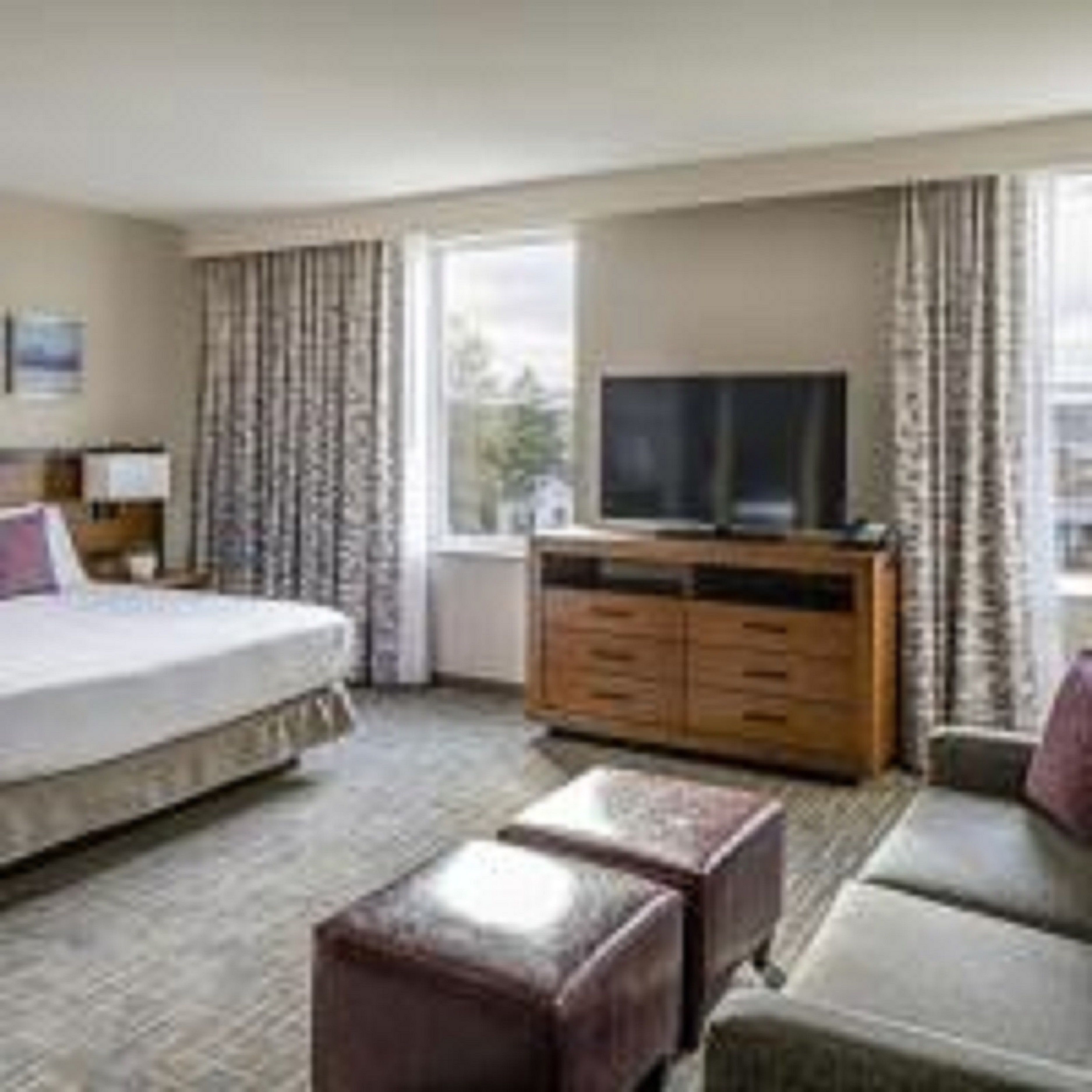 Une chambre d’hôtel avec un lit, une télévision, une commode en bois et un canapé.