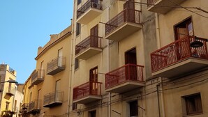 Un immeuble à plusieurs étages doté de balcons, avec des voitures garées et une signalisation bien visible.