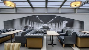 A modern restaurant with a long, narrow seating area featuring leather booths and tables.
