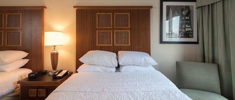 A hotel room with a large bed, two bedside tables, a lamp, a framed picture on the wall, and a chair.