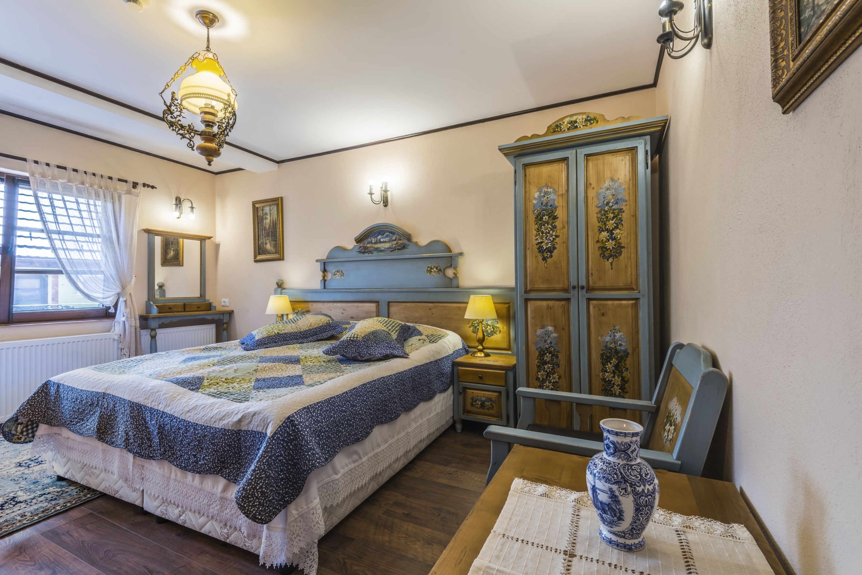 A bedroom with a bed, bedside tables, a dresser, and a window with curtains.