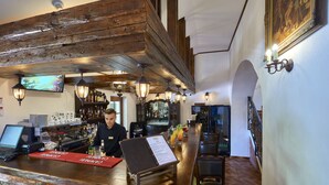 Een bar met een houten plafond, een toog en een menukaartstandaard.