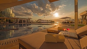 A poolside area with lounge chairs and umbrellas, a clear sky, and a sunset. - Okada Manila (Parañaque)