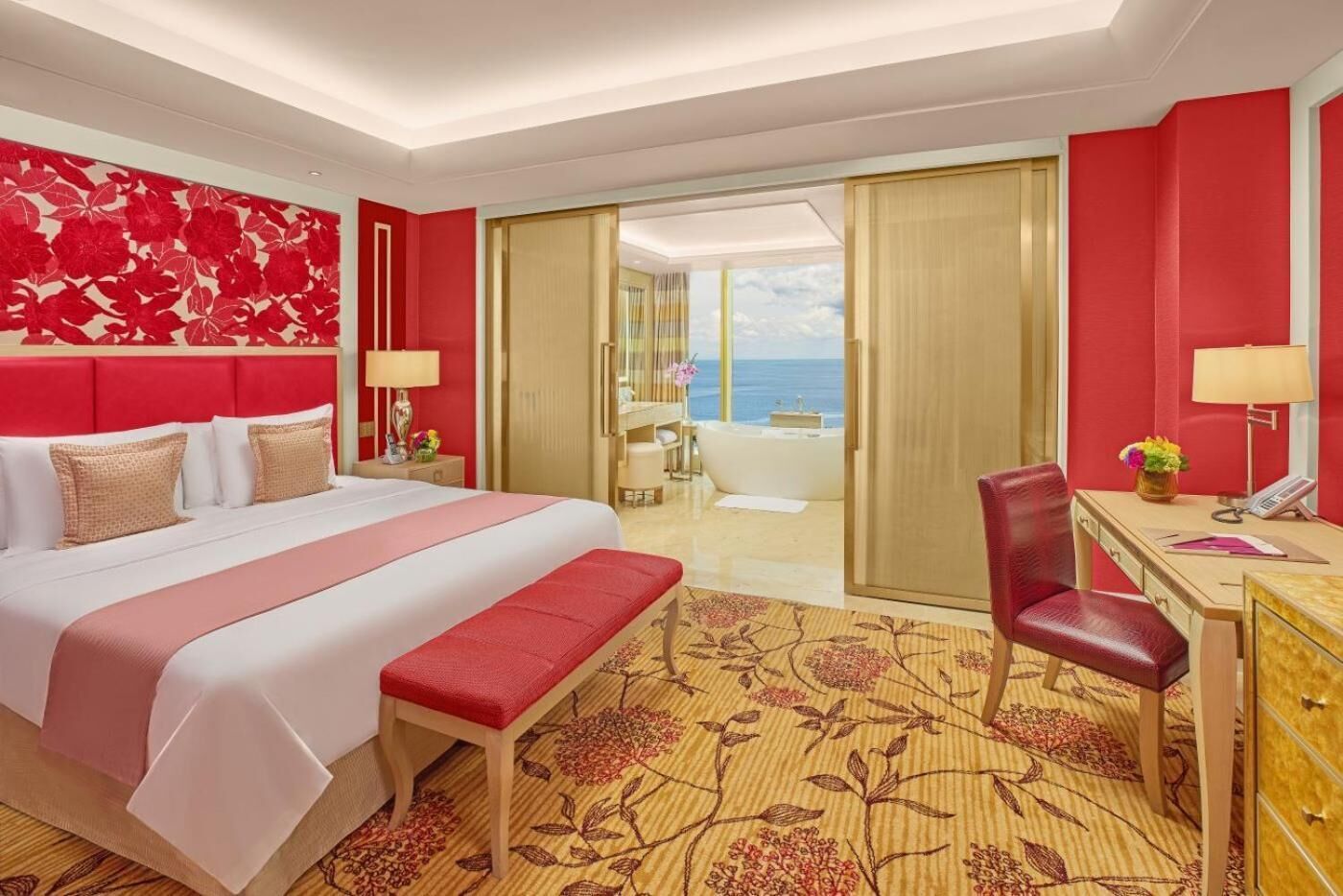 Une chambre d’hôtel avec un grand lit, un bureau, une chaise et une vue sur l’océan.