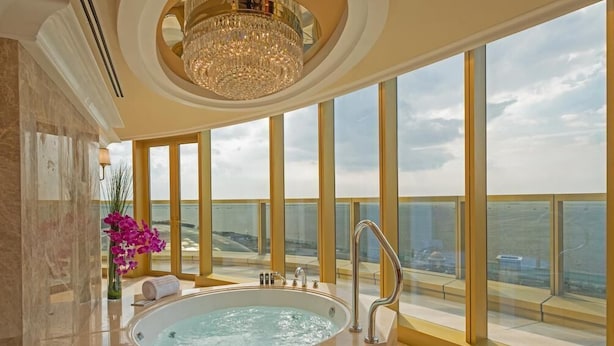 A luxurious bathroom with a large bathtub, a chandelier, and a view of the ocean. - Okada Manila (Parañaque)