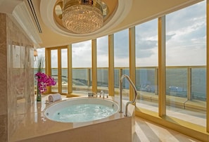 A luxurious bathroom with a large bathtub, a chandelier, and a view of the ocean. - Okada Manila (Parañaque)