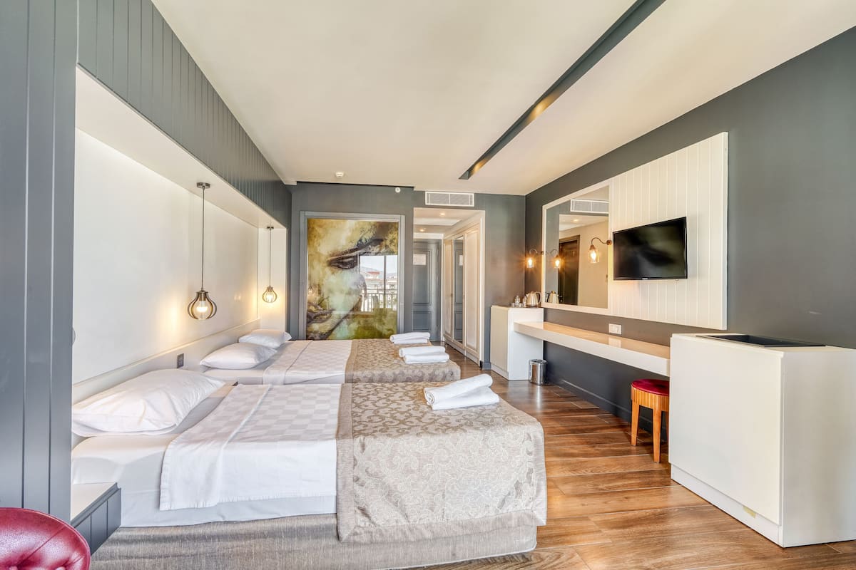A hotel room with a long bed, a TV, a desk, and a bathroom.