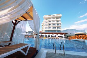 A pool area with lounge chairs, a pool, and a building with balconies in the background. - Sey Beach Hotel & Spa (Alanya)