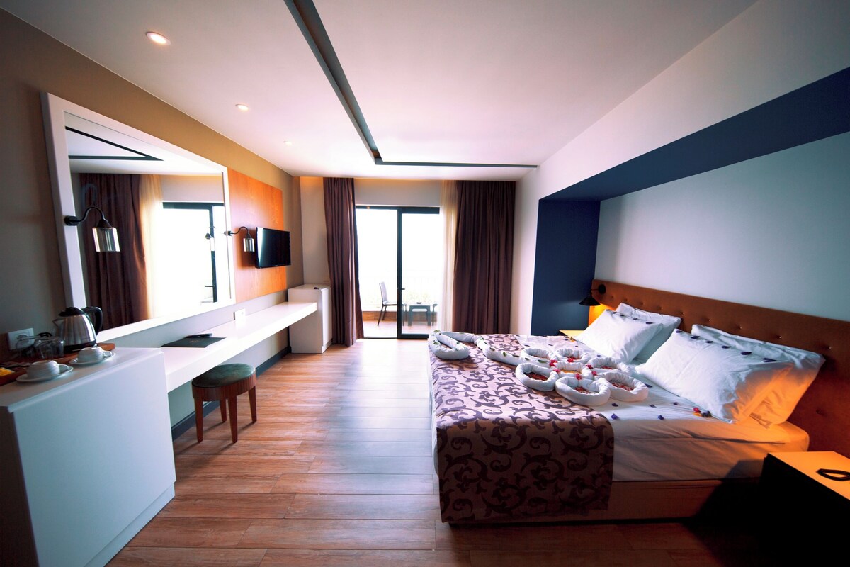 A hotel room with a bed, a desk, a chair, and a TV.