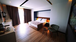 A modern hotel room with a large bed, a desk with a coffee maker, and a chair. - Sey Beach Hotel & Spa (Alanya)