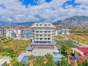 A multi-story hotel with a swimming pool, outdoor seating, and a view of mountains. - Sey Beach Hotel & Spa (Alanya)