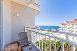 A balcony with a chair and table, overlooking a beach and buildings. - Sey Beach Hotel & Spa (Alanya)