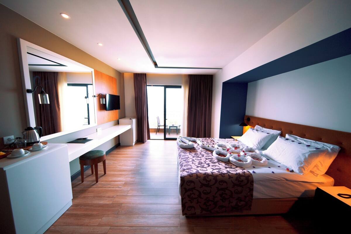 A hotel room with a bed, a desk, a chair, and a TV.