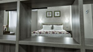 Een slaapkamer met een houten hoofdbord, een bloemenbedekking en twee ingelijste foto’s aan de muur.
