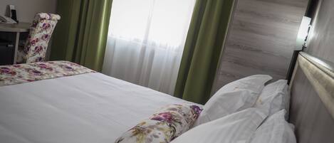A hotel room with a bed, a chair, and a desk with a telephone.
