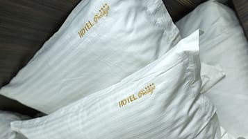 A bed with white pillows and a floral-patterned pillow.