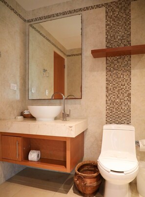 A bathroom with a white sink, a mirror, a toilet, and a wicker basket.