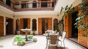 A courtyard with a fountain, a table with chairs, and potted plants. - Riad Dar Saidi (Rabat)