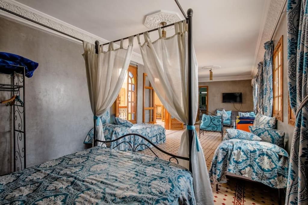 Une chambre avec un lit à baldaquin, deux petits lits et un téléviseur fixé au mur.