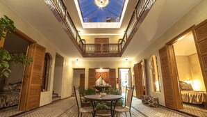 A spacious room with a high ceiling, a central round table, and a balcony with ornate railings. - Riad Dar Saidi (Rabat)