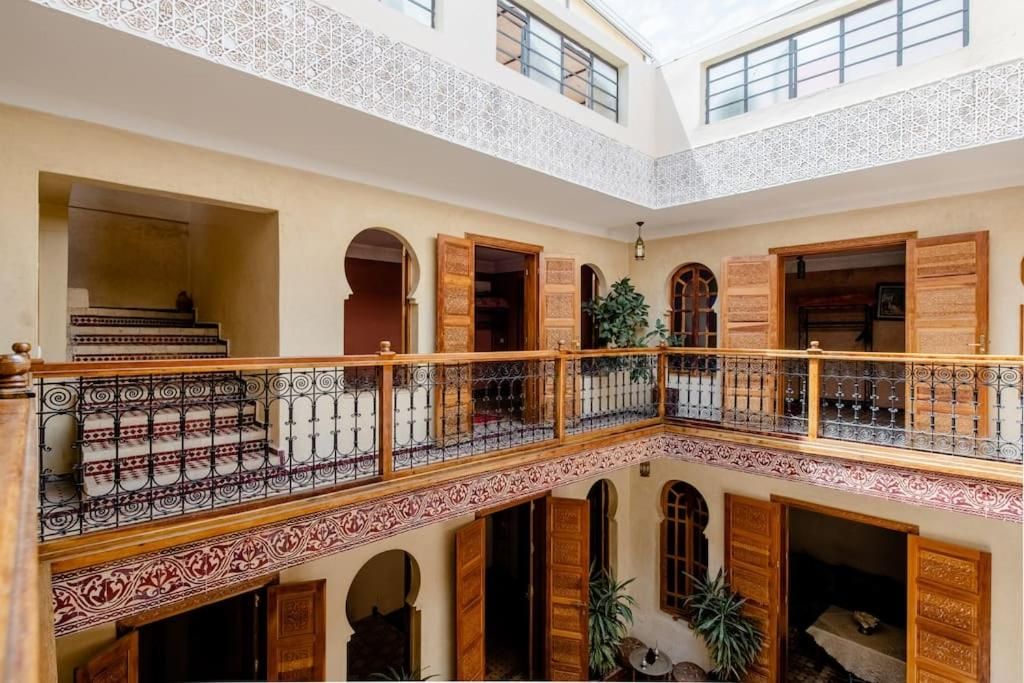 Un interior de varios niveles con un espacio central abierto, balcones con barandillas ornamentales y puertas de madera tradicionales.