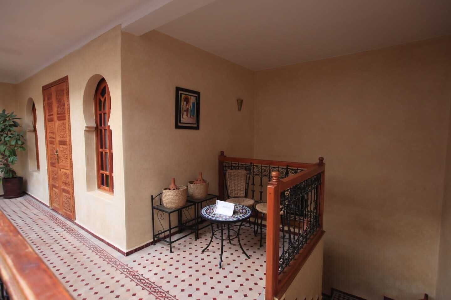 A corridor with a wooden door, a small table with chairs, and a potted plant.
