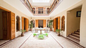A spacious courtyard with a central fountain, surrounded by ornate wooden doors and potted plants. - Riad Dar Saidi (Rabat)