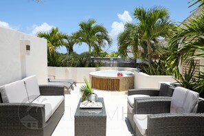 An outdoor patio area with wicker furniture, a hot tub, and tropical plants. - Turquesa Penthouse 2 BDRM sleeps 5 (Tulum)