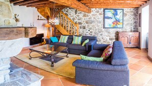 A living room with a stone wall, a staircase, and a wooden ceiling.