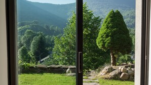 A sliding glass door leading to a garden with a stone pathway, a tree, and a mountain in the background.