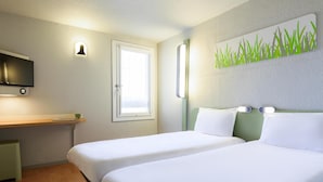 A hotel room with two beds, a TV, a window, and a wall-mounted light fixture. - ibis budget Avignon Nord Le Pontet (Le Pontet)