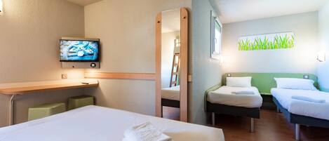 A hotel room with a large bed, a desk, a TV, and a mirror.
