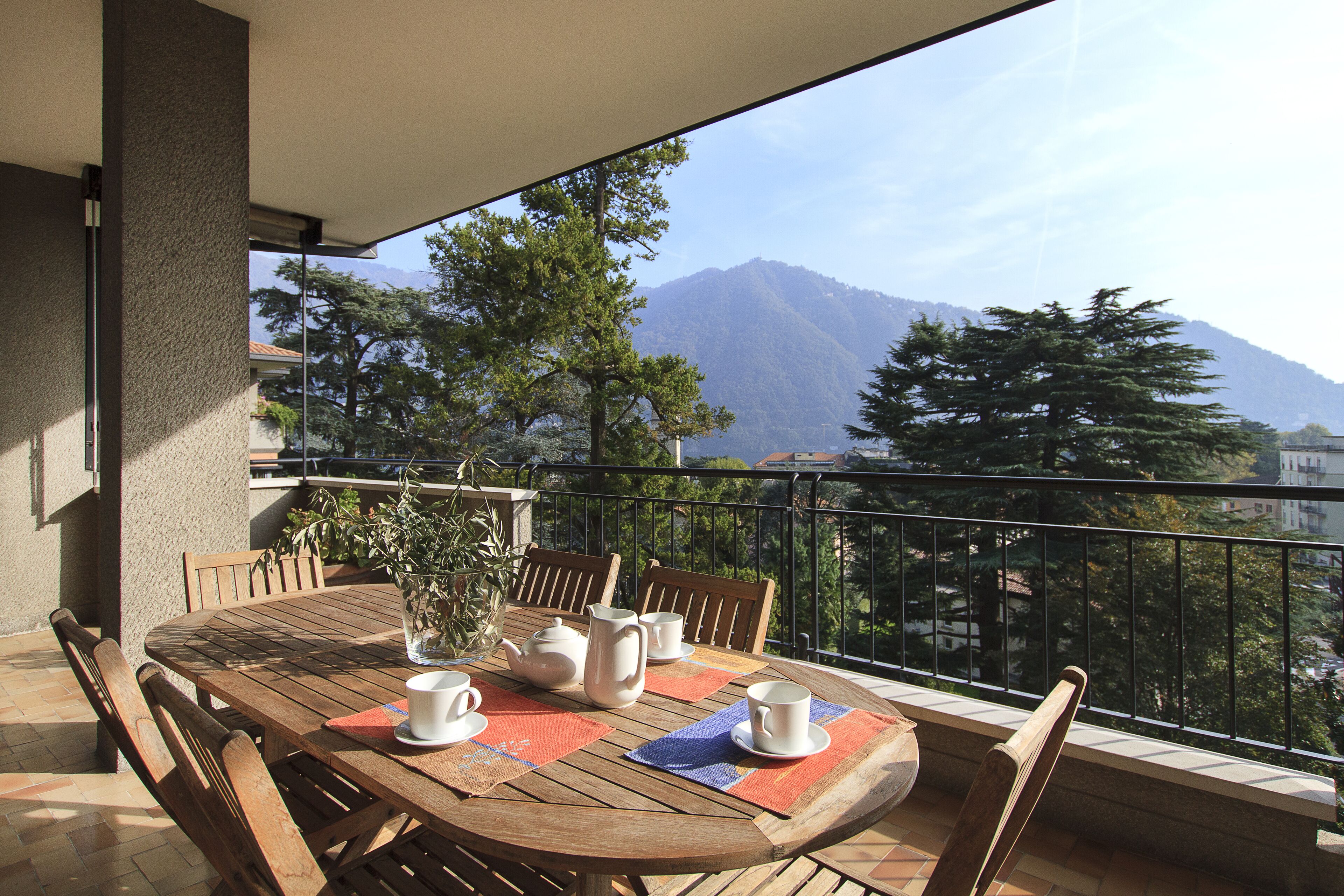 Une table en bois, dressée pour le thé, sur un balcon offrant une vue sur la montagne.