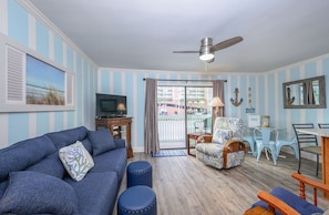 Relax in this stylish living room with a large TV, sofa, and armchair, plus a balcony with a view.