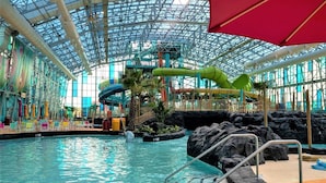 En inomhusbadpark med en stor pool, vattenrutschkanor och ett glastak.