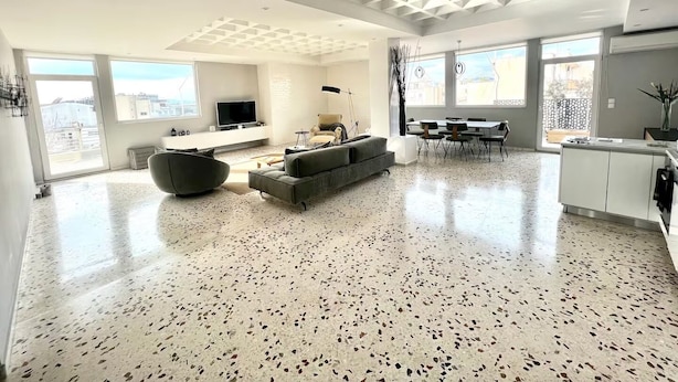 A spacious living area with a large TV, seating, and a kitchen area.