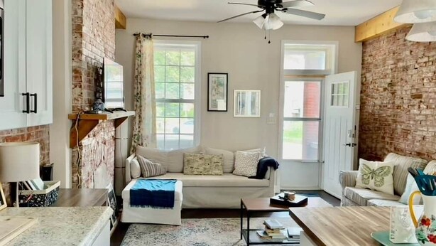 A cozy living room with a fireplace, a sofa, a coffee table, and a ceiling fan. - Charming 1BR Flat. The Hill/SW Gardens District (St. Louis)