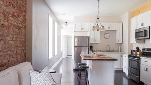 A modern kitchen with white cabinets, a stainless steel refrigerator, and a built-in oven. - Charming 1BR Flat. The Hill/SW Gardens District (St. Louis)