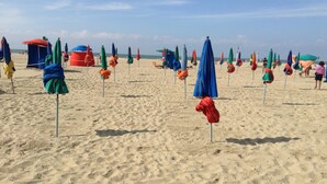 Ein Strand mit Reihen von Sonnenschirmen und Liegestühlen.