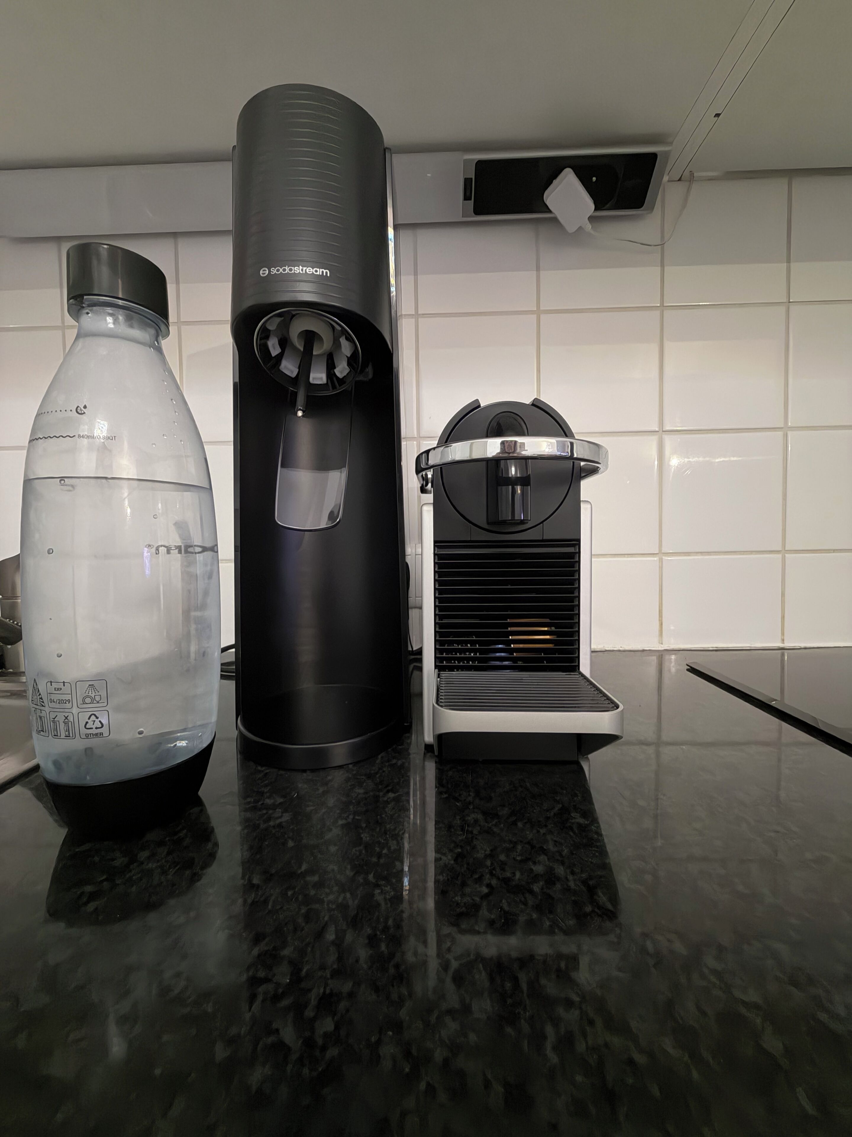 Una encimera de cocina con una botella de agua, una máquina de café y una cafetera.