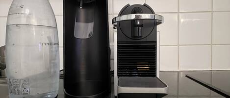 Una encimera de cocina con una botella de agua, una máquina de café y una cafetera.