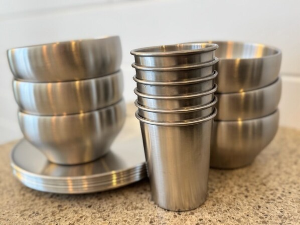 A stack of stainless steel bowls and a cup on a countertop.