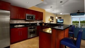Une cuisine moderne avec des meubles de rangement rouges, des appareils électroménagers en acier inoxydable et un îlot central.