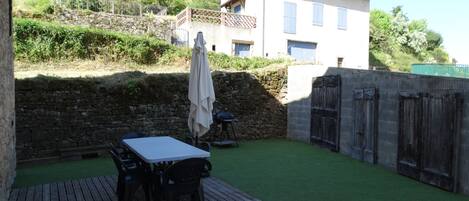 A patio with a table and chairs, a small umbrella, and a stone wall.