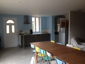 A kitchen with a wooden table and colorful chairs, a sink, and modern appliances.