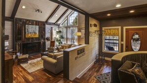 A spacious living area with a fireplace, a sofa, and a coffee table. There is a sign that reads "SKILIFT" and a window with curtains. - Ranked #1 by VRBO in Flagstaff for 4 years! AC, Pets and Hot Tub! (Flagstaff)