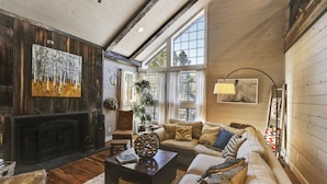 A cozy living room with a fireplace, large windows, and a mix of wooden and upholstered furniture. - Ranked #1 by VRBO in Flagstaff for 4 years! AC, Pets and Hot Tub! (Flagstaff)