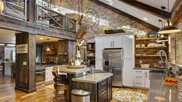 A spacious kitchen with a central island, wooden flooring, and a brick wall. - Ranked #1 by VRBO in Flagstaff for 4 years! AC, Pets and Hot Tub! (Flagstaff)
