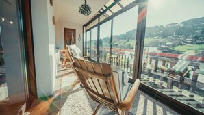 A room with a large window, a wooden chair, and a view of a landscape.